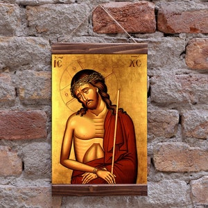 Può includere: Un'icona religiosa che raffigura Gesù Cristo con una corona di spine, che indossa una tunica rossa e tiene un bastone. L'icona è dipinta in uno stile tradizionale con accenti dorati e il testo "IC XC" nell'angolo in alto a destra.