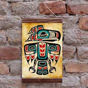 May include: A framed print featuring a stylized Native American design of a bird, with black, red, and teal colors. The artwork is displayed on a textured, off-white background, and framed with dark wood. The print is hanging on a brick wall.