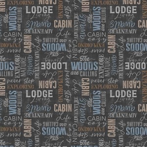 May include: A dark gray fabric featuring a repeating typographic pattern with the words Lodge, Cabin, Woods, Adventure, Exploring, Nature, and phrases like The Woods are calling, Cabin life, and never stop exploring in white, blue, and tan.