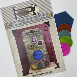 May include: A pattern for a primitive penny flowerpot wall hanging. The pattern includes a sheep illustration and the text "In The Patch Designs". The pattern is accompanied by a set of felt pieces in various colors.