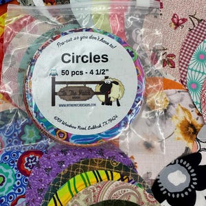May include: A clear plastic bag filled with pre-cut fabric circles in various colors and patterns. The bag has a label that reads "Circles 50 pcs - 4 1/2"" and features a sheep illustration. The fabric circles are ready for crafting projects.