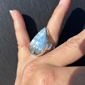 May include: A teardrop-shaped ring with a silver band and a white and gray agate stone.