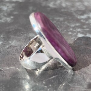 Peut inclure: Bague en argent avec une grosse pierre ovale violette &agrave; l'aspect marbr&eacute;. L'anneau de la bague est poli. Le poin&ccedil;on "925" est visible &agrave; l'int&eacute;rieur de l'anneau. Bijou.