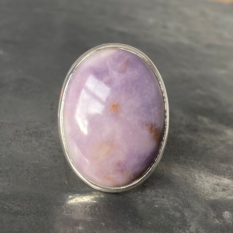 May include: A silver ring with a large oval-shaped purple and white gemstone.