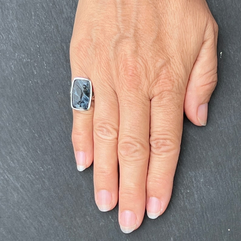 Op de afbeelding: Een zilveren ring met een rechthoekige blauwe en witte agaat-steen.