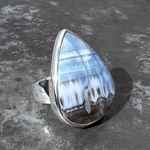 May include: A silver ring with a teardrop-shaped blue and white agate stone.