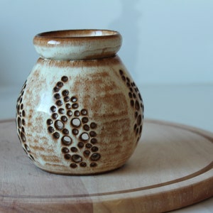 May include: A white ceramic oil diffuser with a brown glaze and a decorative pattern of circles. The diffuser has a round shape and a wide opening at the top.