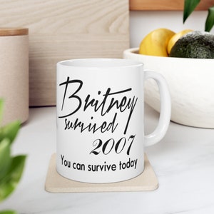 May include: White ceramic mug with black text that reads "Britney survived 2007 You can survive today".