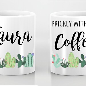 May include: Two white coffee mugs with a cactus theme. One mug says "Laura" and the other says "Prickly Without Coffee".