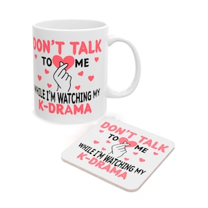 May include: White ceramic mug and coaster set. The mug and coaster have the text "DON'T TALK TO ME WHILE I'M WATCHING MY K-DRAMA" in pink and black, with heart and hand graphics.