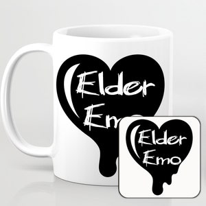 Puede incluir: Taza de cerámica blanca con un diseño de corazón negro que dice "Elder Emo" y un posavasos de corazón negro a juego.