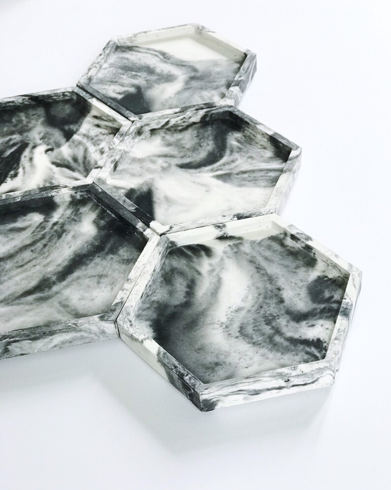 Puede incluir: Un conjunto de seis bandejas hexagonales con un dise&ntilde;o veteado en tonos grises y blancos. Las bandejas est&aacute;n dispuestas juntas, mostrando el patr&oacute;n &uacute;nico y la forma geom&eacute;trica. Las bandejas tienen una est&eacute;tica moderna y minimalista.