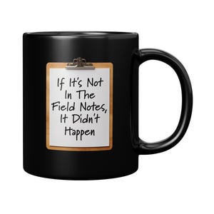 May include: Black coffee mug featuring a white notepad design. The notepad has a silver clip and the text "If It's Not In The Field Notes, It Didn't Happen" in black. The mug has a large, curved handle.
