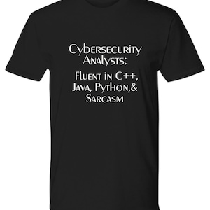 May include: Black t-shirt with white text that reads "Cybersecurity Analysts: Fluent in C++, Java, Python, & Sarcasm".