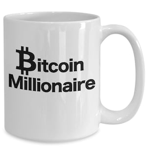 Könnte beinhalten: Weiße Keramik-Kaffeetasse mit einem schwarzen Bitcoin-Symbol und dem Text "Bitcoin Millionaire" auf der Vorderseite.