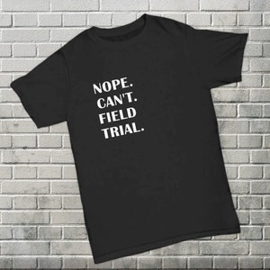 May include: Black t-shirt with white text that reads "NOPE. CAN'T. FIELD TRIAL."