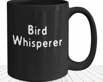 May include: Black ceramic coffee mug with white text that reads "Bird Whisperer".