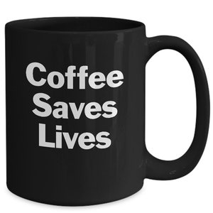 Könnte beinhalten: Schwarze Kaffeetasse mit weißem Text, der "Coffee Saves Lives" lautet.