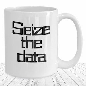 May include: White ceramic coffee mug with a black graphic that says "Seize the data".
