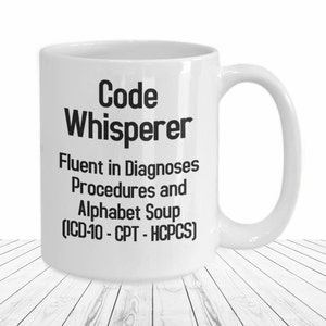 May include: White ceramic coffee mug with black text that reads "Code Whisperer Fluent in Diagnoses Procedures and Alphabet Soup (ICD-10 - CPT - HCPCS)"