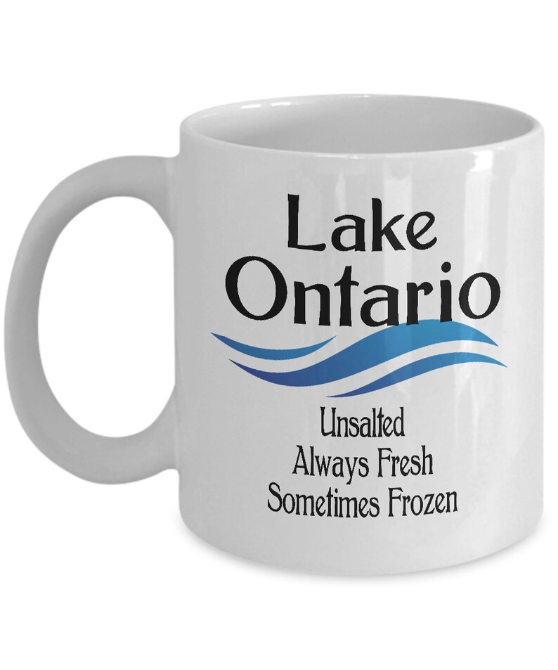 May include: White ceramic coffee mug with a black and blue design. The mug says "Lake Ontario" with a blue wave design and the text "Unsalted Always Fresh Sometimes Frozen".