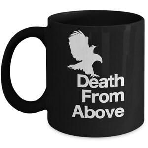 以下が含まれることがあります： 白い鷲のシルエットと「Death From Above」という文字が書かれた黒いコーヒーカップ。