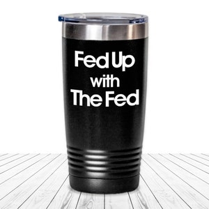 May include: Black stainless steel travel mug with a white inscription that reads "Fed Up with The Fed".
