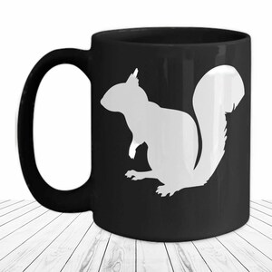 May include: Black coffee mug with a white silhouette of a squirrel on the front.