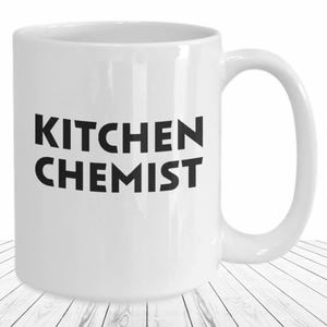 May include: White ceramic coffee mug with black text that reads "Kitchen Chemist".