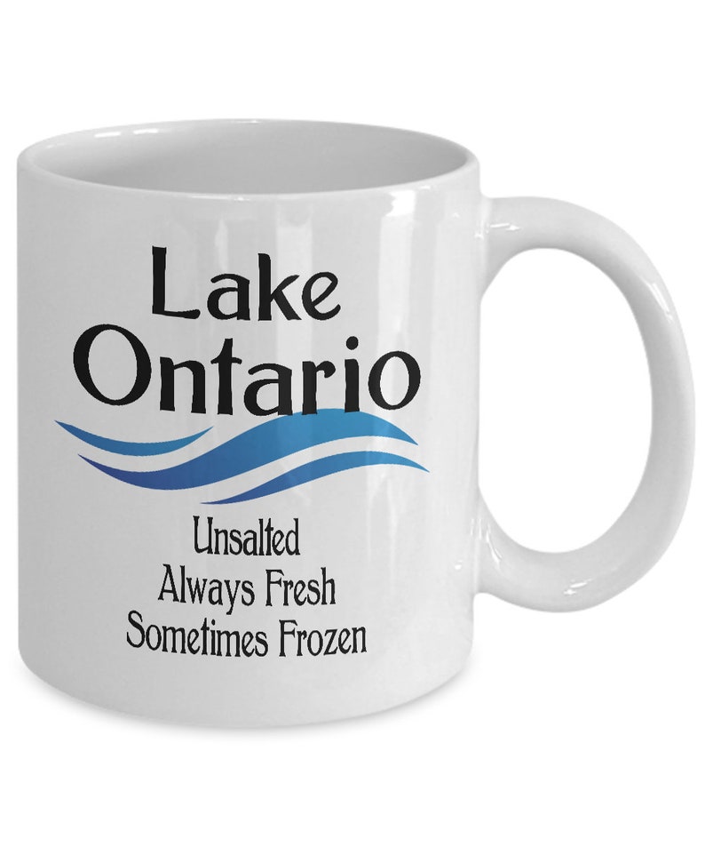 May include: White ceramic coffee mug with a blue and white wave design and the text "Lake Ontario Unsalted Always Fresh Sometimes Frozen".