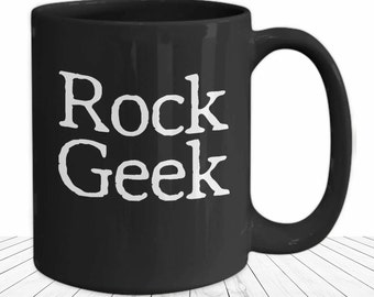 May include: Black ceramic coffee mug with a white inscription that reads "Rock Geek".