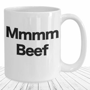 May include: White ceramic coffee mug with black text that reads "Mmmmm Beef".