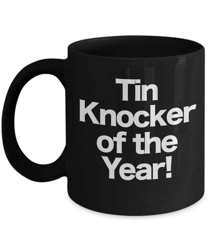 May include: Black ceramic coffee mug with white text that reads "Tin Knocker of the Year!"