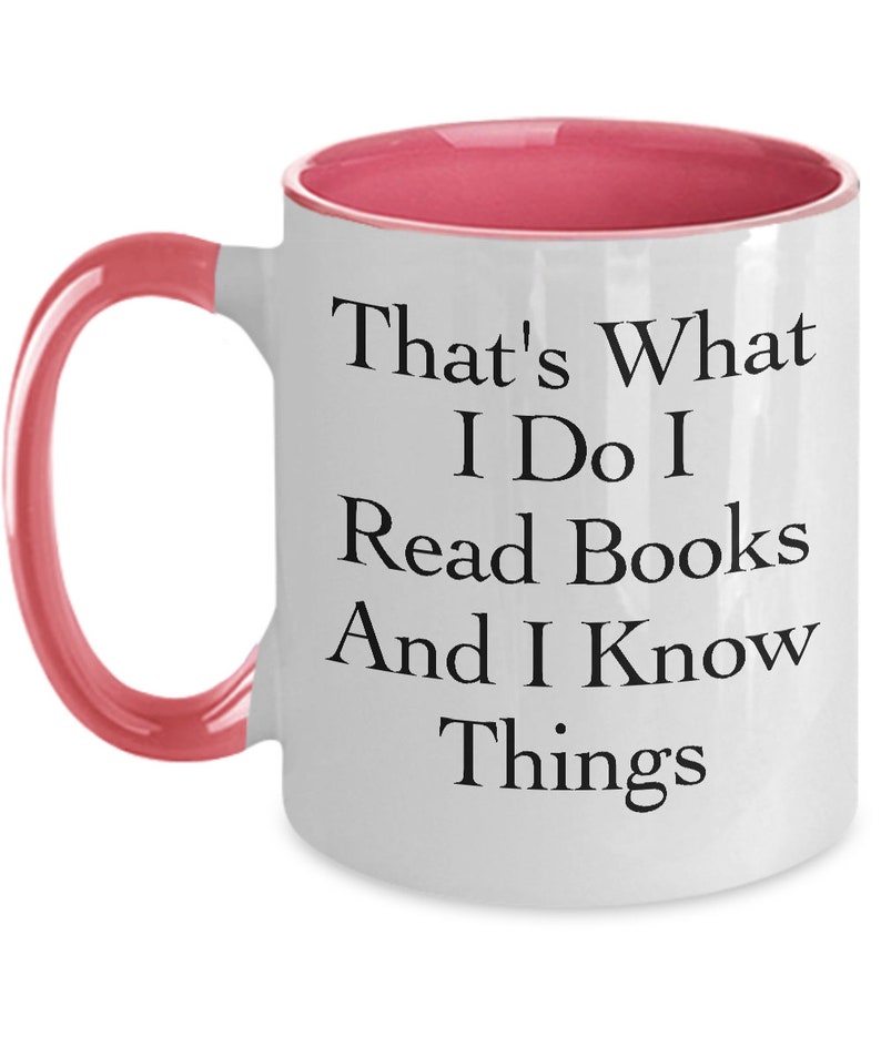 May include: White coffee mug with a pink rim and handle. The mug has black text that reads "That's What I Do I Read Books And I Know Things."