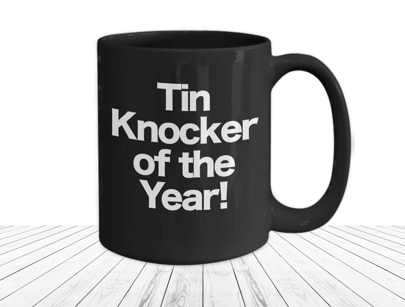 Black Ceramic Coffee Cup 15 fl oz Mug with bold white font in the center that says "Tin Knocker of the Year"