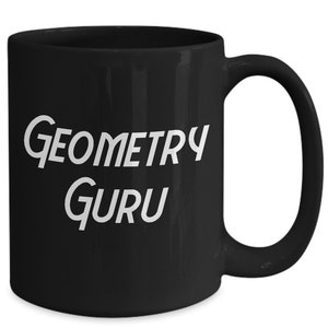 May include: Black ceramic mug with a white handle. The mug features the words "Geometry Guru" in a white, stylized font. The mug is designed for hot drinks.