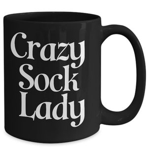 May include: Black ceramic coffee mug with white text that reads "Crazy Sock Lady".