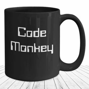 May include: Black ceramic coffee mug with white text that reads "Code Monkey".