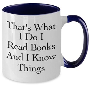 May include: White ceramic coffee mug with a blue rim and handle. The mug has black text that reads "That's What I Do I Read Books And I Know Things."