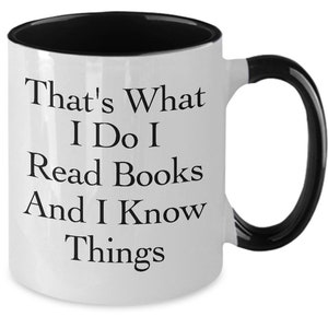 White ceramic two tone coffee mug with black handle and interior featuring text reading "That's What I Do I Read Books And I Know Things" funny book lover mug available in 11 oz and 15 oz sizes