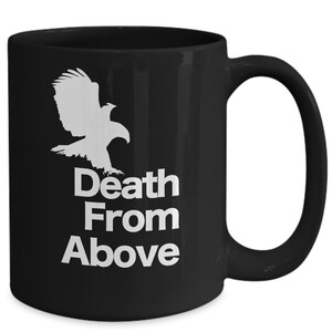 以下が含まれることがあります： 白い鷲のシルエットと「Death From Above」という文字が書かれた黒いセラミック製のコーヒーカップです。
