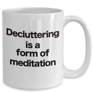 May include: White ceramic coffee mug with black text that reads "Decluttering is a form of meditation".