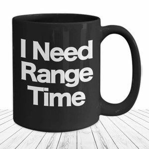 May include: Black coffee mug with white text that reads "I Need Range Time".