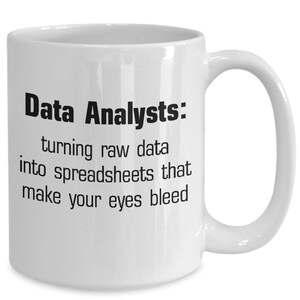 May include: White ceramic coffee mug with black text that reads "Data Analysts: turning raw data into spreadsheets that make your eyes bleed."