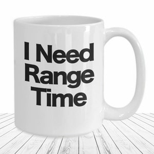 May include: White ceramic coffee mug with black text that reads "I Need Range Time".