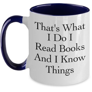 May include: White ceramic coffee mug with a blue rim and handle. The mug has black text that reads "That's What I Do I Read Books And I Know Things."