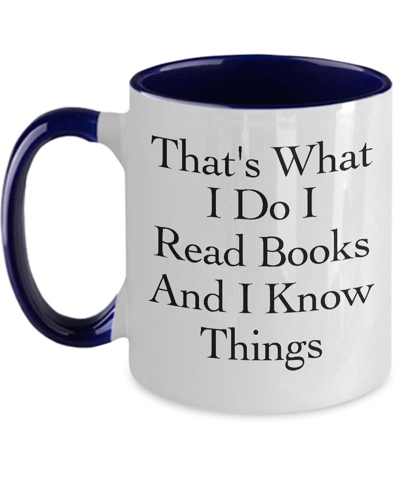 May include: White ceramic coffee mug with a blue rim and handle. The mug has black text that reads "That's What I Do I Read Books And I Know Things."