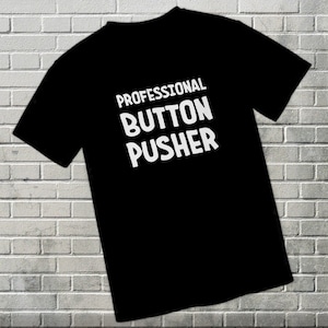 May include: A black t-shirt with white text that reads "Professional Button Pusher".