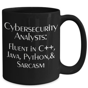 Könnte beinhalten: Schwarze Kaffeetasse mit weißem Text, der "Cybersecurity Analysts: Fluent in C++, JAVA, PYTHON, & SARCASM" lautet.
