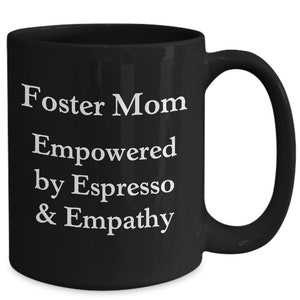 May include: Black coffee mug with white text that reads "Foster Mom Empowered by Espresso & Empathy".